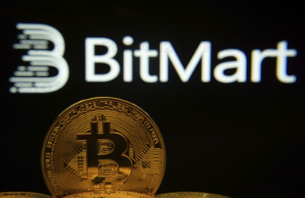 Dhaka, Bangladesh- 03 Sep 2025: Close-up of Bitcoin coins with the Bitmart logo visible on a screen in the background