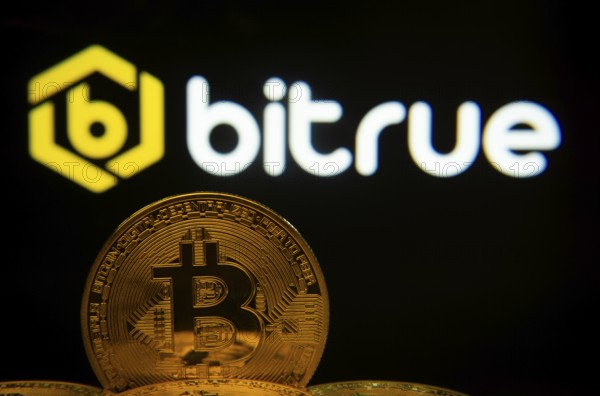 Dhaka, Bangladesh- 03 Sep 2025: Close-up of Bitcoin coins with the Bitrue logo visible on a screen in the background