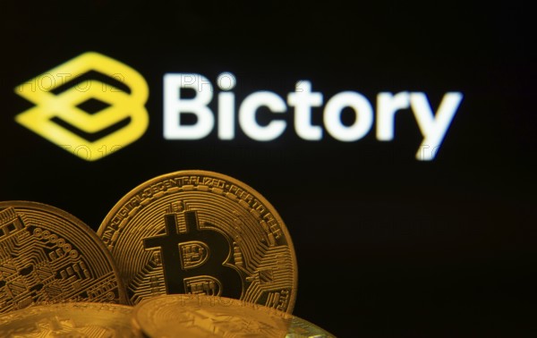 Dhaka, Bangladesh- 09 Sep 2025: Close-up of Bitcoin coins with the Bictory logo visible on a screen in the background