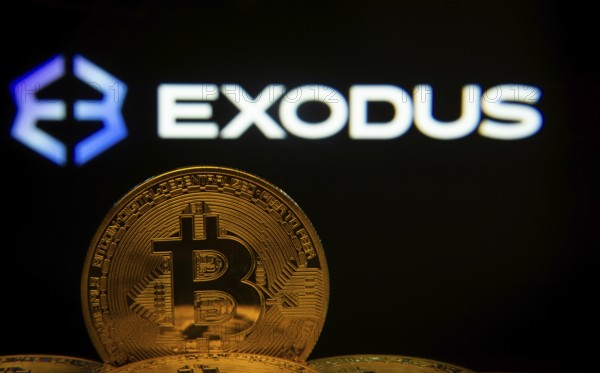 Dhaka, Bangladesh- 06 Sep 2025: Close-up of Bitcoin coins with the Exodus logo visible on a screen in the background