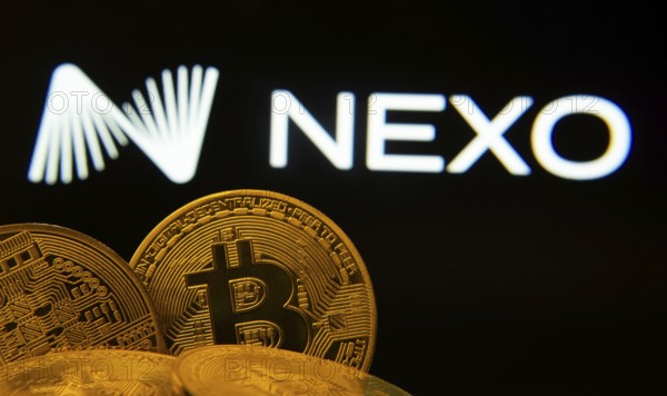 Dhaka, Bangladesh- 06 Sep 2025: Close-up of Bitcoin coins with the Nexo logo visible on a screen in the background
