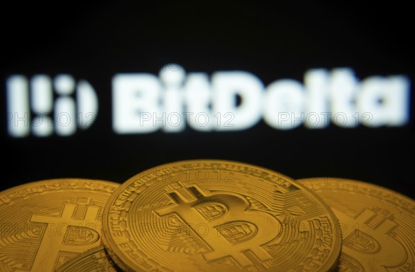 Dhaka, Bangladesh- 02 June 2025: Close-up of Bitcoin coins with the BitDelta logo visible on a screen in the background