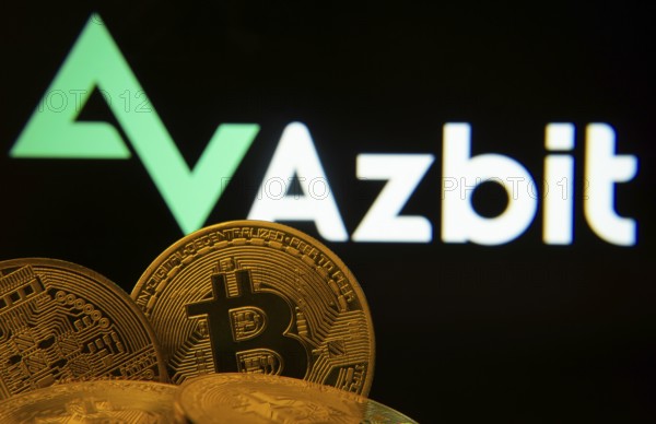 Dhaka, Bangladesh- 02 June 2025: Close-up of Bitcoin coins with the Azbit logo visible on a screen in the background
