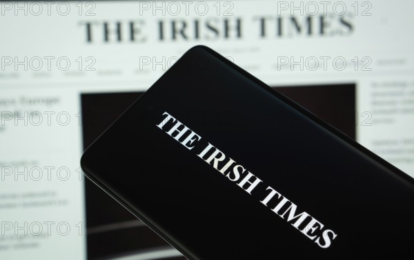 Dhaka, Bangladesh - 18 March 2025: The logo of The Irish times is displayed on a smartphone screen, and the website is visible on a computer screen in the background