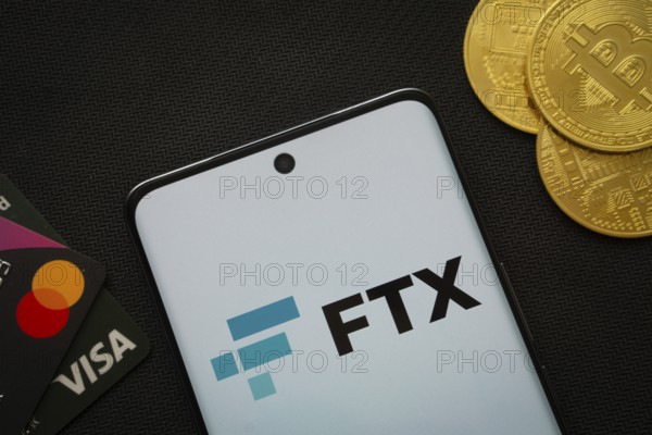 Dhaka, Bangladesh- 26 Aug 2025: Smartphone displaying FTX logo surrounded by Bitcoin coins and payment cards