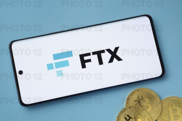 Dhaka, Bangladesh- 26 Aug 2025: FTX logo on smartphone screen near Bitcoin coin and QR code on blue background