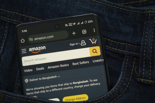 Dhaka, Bangladesh- 15 June 2025: A smartphone displaying the Amazon.com web interface peeks out of a denim pocket