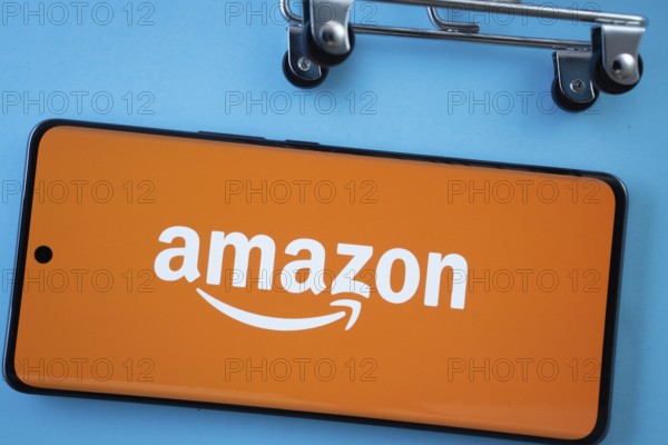 Dhaka, Bangladesh- 03 July 2025: Smartphone screen showing the Amazon logo with shopping cart wheels on a blue background
