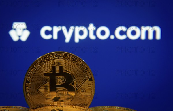 Dhaka, Bangladesh- 26 Aug 2025: Close-up of Bitcoin coins with the Crypto.com logo visible on a screen in the background
