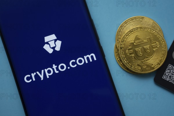 Dhaka, Bangladesh- 26 Aug 2025: Crypto.com logo on smartphone screen near Bitcoin coin and QR code on blue background