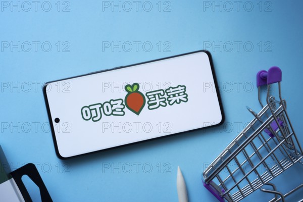 Dhaka, Bangladesh- 03 July 2025: Smartphone displaying Dingdong Maicai logo with shopping cart on a blue background