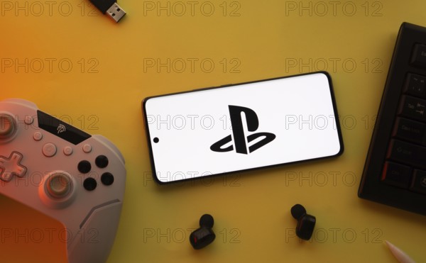 Dhaka, Bangladesh- 26 July 2025: A close-up of a gamepad with the PlayStation seen on smartphone