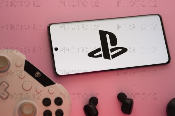 Dhaka, Bangladesh- 15 Aug 2025: A close-up of a gamepad with the PlayStation seen on smartphone