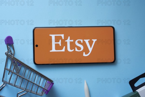 Dhaka, Bangladesh- 03 July 2025: Smartphone displaying Etsy logo with shopping cart on a blue background
