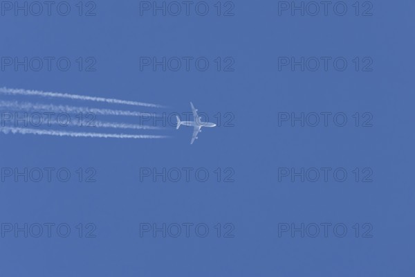 Airbus A340-300 jet aircraft of Lufthansa airlines in flight in a blue sky with vapour trails or contrails behind, England, United Kingdom