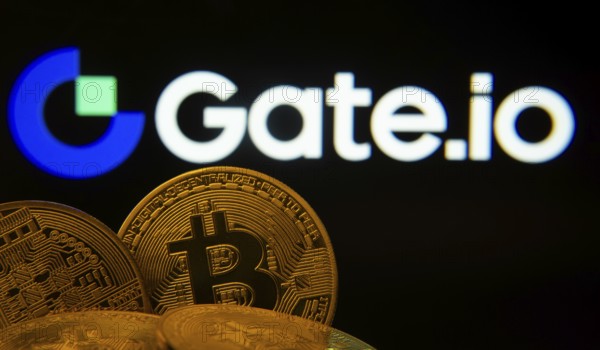 Dhaka, Bangladesh- 08 Aug 2025: Close-up of Bitcoin coins with the Gate.io logo visible on a screen in the background