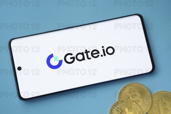 Dhaka, Bangladesh- 22 June 2025: Gate.io logo on smartphone screen near Bitcoin coin and QR code on blue background