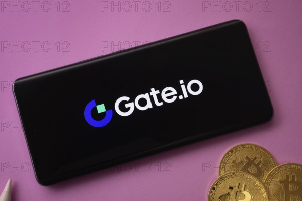 Dhaka, Bangladesh- 22 June 2025: Gate.io logo on smartphone screen near Bitcoin coin and QR code on background