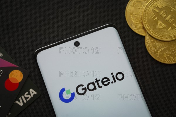 Dhaka, Bangladesh- 27 July 2025: Smartphone displaying Gate.io logo surrounded by Bitcoin coins and payment cards