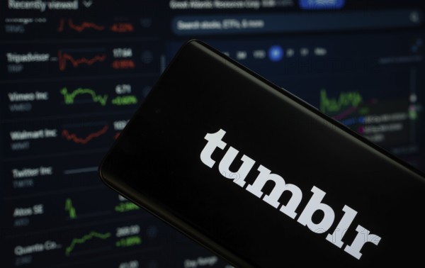 Dhaka, Bangladesh- 08 Aug 2025: Tumblr logo is displayed on a smartphone screen, with a stock graph webpage visible on a computer screen in the background