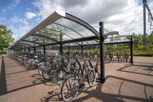 Bicycle parking spaces and boxes on the cycle path in the east of Utrecht, at Utrecht-Lunetten railway station, direct connection of the cycle path to the railway station and bus station, covered bicycle stands, on the Maarschalkerweerdpads cycle path, Netherlands