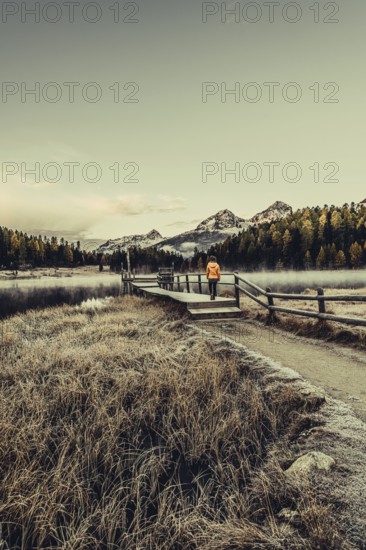 Young woman at Lake Staz near Sankt Moritz in the Engadine in Switzerland. Morning atmosphere with fog in autumn. Reflection of water