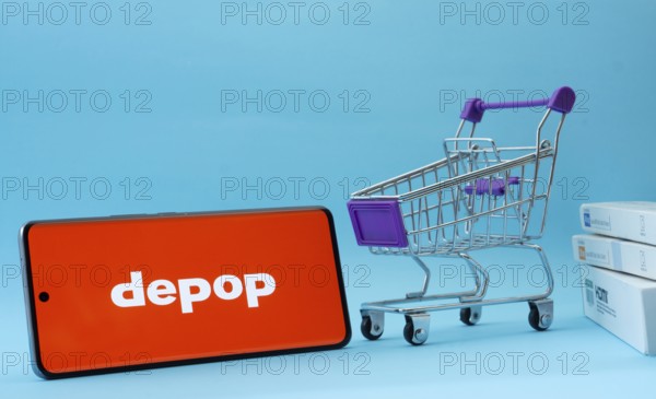 Dhaka, Bangladesh- 03 July 2025: Smartphone with Depop logo next to a small shopping cart and boxes against a blue background