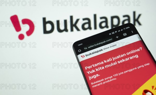 Dhaka, Bangladesh- 03 July 2025: Smartphone displaying Bukalapak web interface against Bukalapak logo background