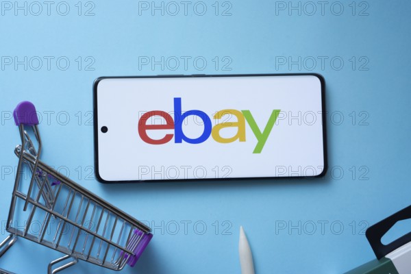 Dhaka, Bangladesh- 03 July 2025: Smartphone displaying eBay logo with shopping cart on a blue background