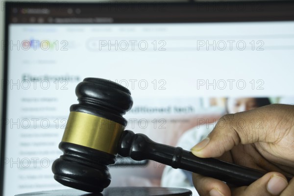 Dhaka, Bangladesh- 20 June 2025: A hand holds a gavel in front of a computer screen displaying eBay's website