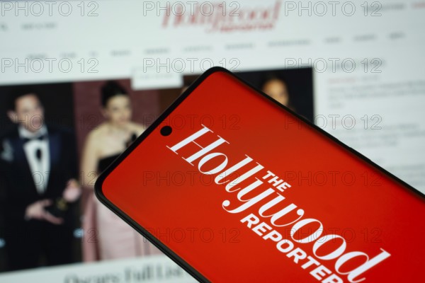 Dhaka, Bangladesh - 18 March 2025: The logo of The Hollywood Reporter is displayed on a smartphone screen, and the website is visible on a computer screen in the background
