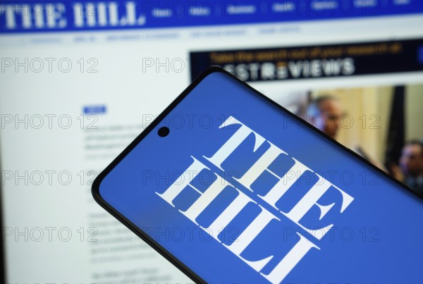 Dhaka, Bangladesh - 18 March 2025: The logo of The Hill is displayed on a smartphone screen, and the website is visible on a computer screen in the background