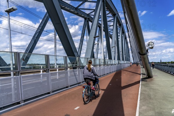 Cycle and pedestrian bridge Snelbinder Brug, over the river Waal near Nijmegen, was added to the existing railway bridge, fast cycle path connection from the city centre of Nijmegen and the new housing estates in the Waalsprong district, Netherlands