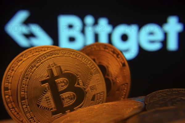 Dhaka, Bangladesh- 27 July 2025: Close-up of Bitcoin coins with the Bitget logo visible on a screen in the background