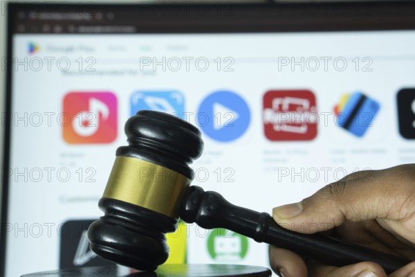Dhaka, Bangladesh- 20 June 2025: A hand holds a gavel in front of a computer screen displaying Google play store website