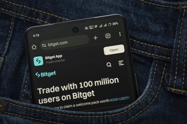 Dhaka, Bangladesh- 15 June 2025: A smartphone displaying the bitget.com web interface peeks out of a denim pocket