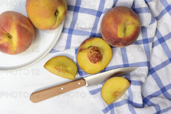 Peach with knife on kitchen towel, peach halves, Prunus persica
