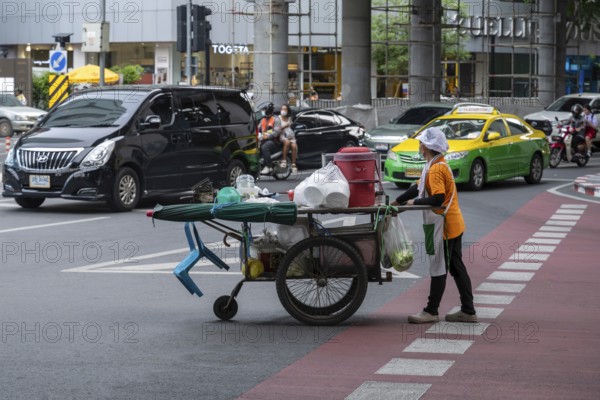Street crossing woman with cookshop, Bangkok, Thailand