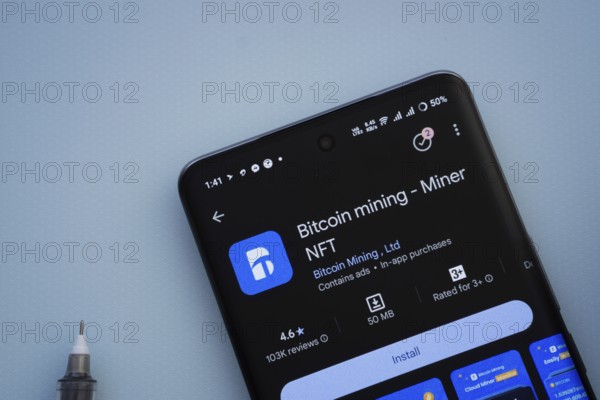 Dhaka, Bangladesh- 29 May 2025: On a blue surface, a smartphone displays the Bitcoin mining app within the Google Play Store