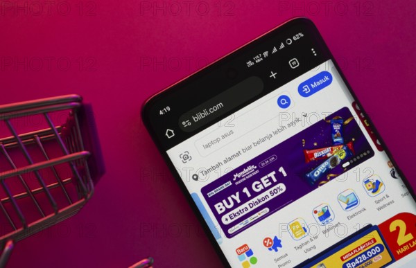 Dhaka, Bangladesh- 23 June 2025: A smartphone displaying the Blibli website with a shopping cart is shown on a vibrant background