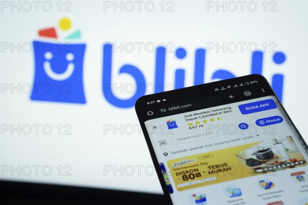 Dhaka, Bangladesh- 03 July 2025: Smartphone displaying Blibli web interface against Blibli logo background