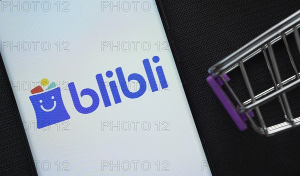Dhaka, Bangladesh- 03 July 2025: A smartphone displaying the Blibli logo next to a miniature shopping cart on a background
