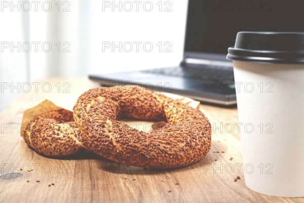 Simits with coffee on a wooden table, with a laptop, in a cozy working environment, snack, breakfast, no people