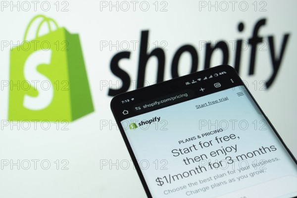Dhaka, Bangladesh- 03 July 2025: Smartphone displaying Shopify web interface against Shopify logo background