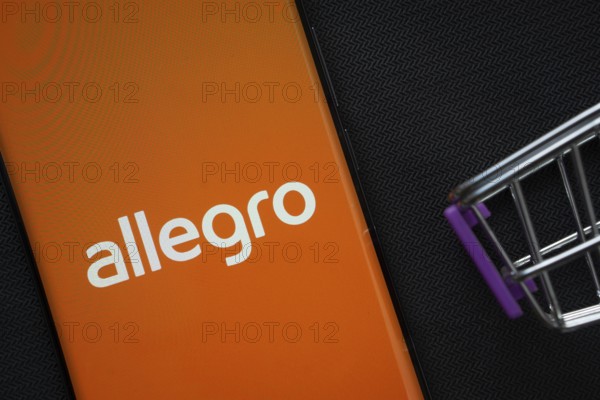 Dhaka, Bangladesh- 03 July 2025: A smartphone displaying the Allegro logo next to a miniature shopping cart on a background