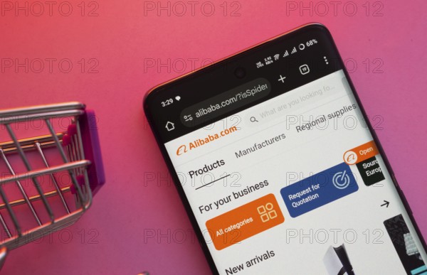 Dhaka, Bangladesh- 23 June 2025: A smartphone displaying the Alibaba website with a shopping cart is shown on a vibrant background
