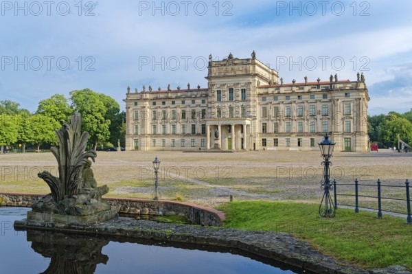 Ludwigslust Palace, built in the Baroque period and characterised by Classicism, with the palace square. In the foreground is the basin, a water basin with cascades and stone figures. Ludwigslust, Mecklenburg-Western Pomerania, Germany
