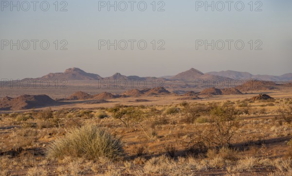 Desert landscape in the evening light at sunset, barren landscape with hills of stacked rocks, Erongo, Damaraland, Namibia