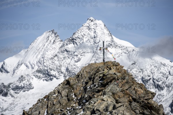 Summit cross of the summit Böses Weibl, behind summit of the Großglockner with snow, Schober group, Hohe Tauern National Park, Carinthia, Austria