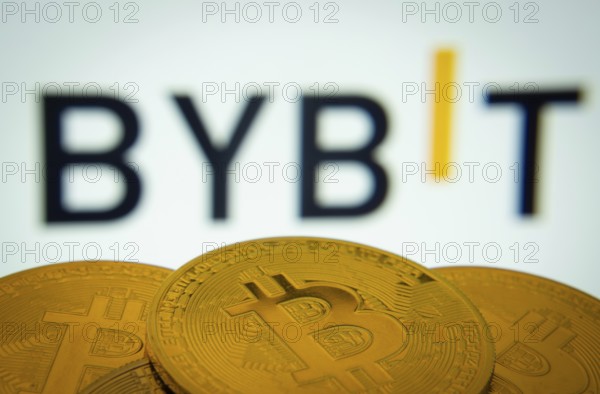 Dhaka, Bangladesh- 15 July 2025: Close-up of Bitcoin coins with the Bybit logo visible on a screen in the background